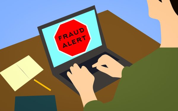 hombre usando una laptop cuya pantalla dice "fraud alert"